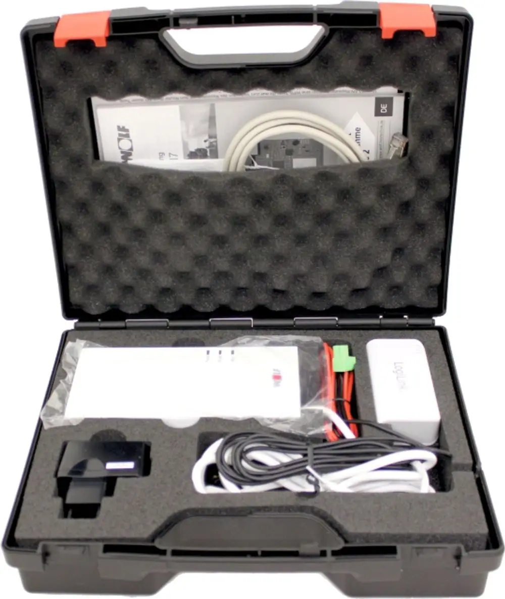 Schwarze Transportbox mit Schaumstoffeinlage und verschiedenen Komponenten, darunter Kabel und eine Anleitung, für die Verwendung mit Wolf-Produkten.